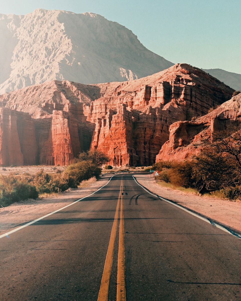 gray asphalt road near brown mountain during daytime